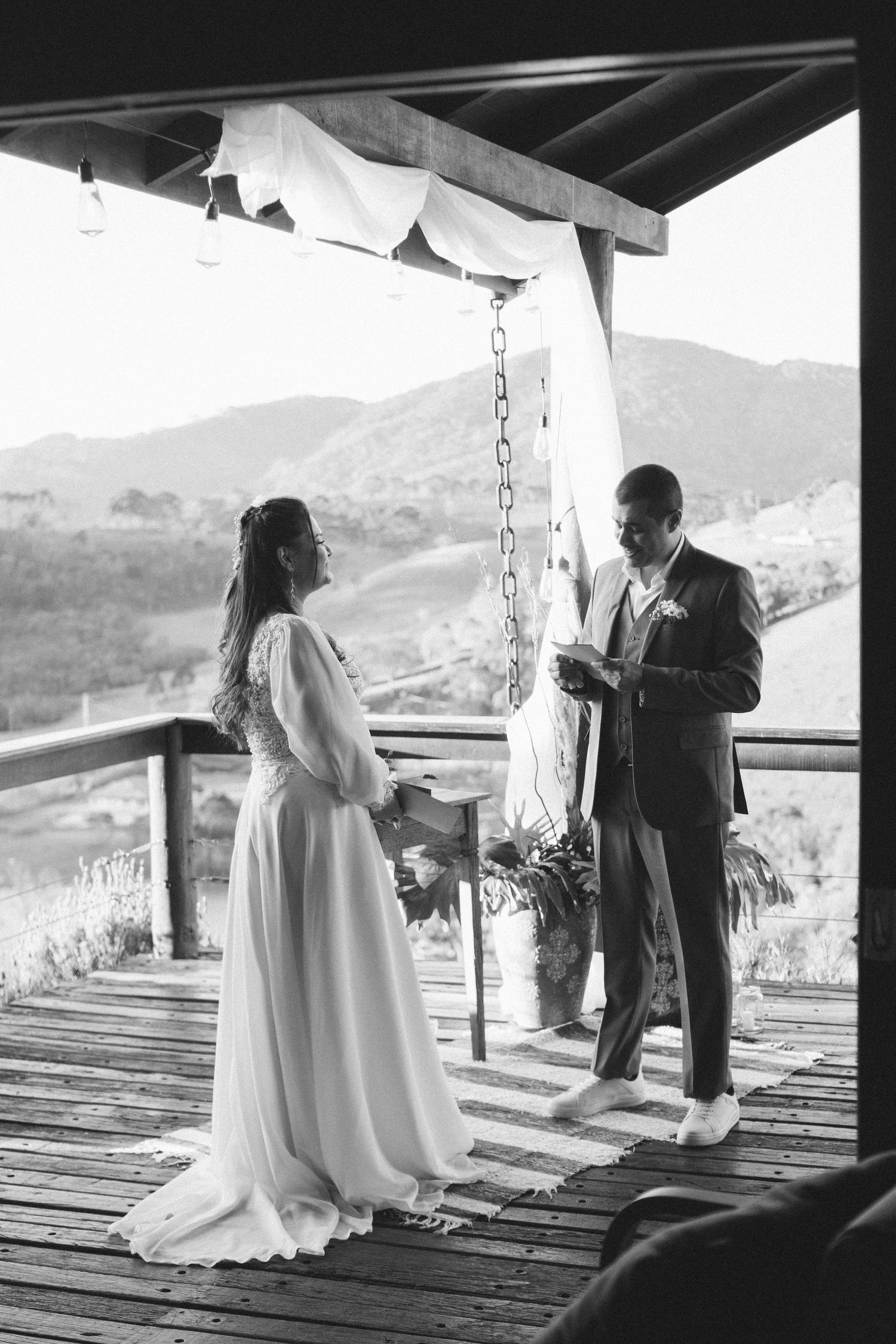 Black and white photo of wedding ceremony on rustic deck with mountain views.