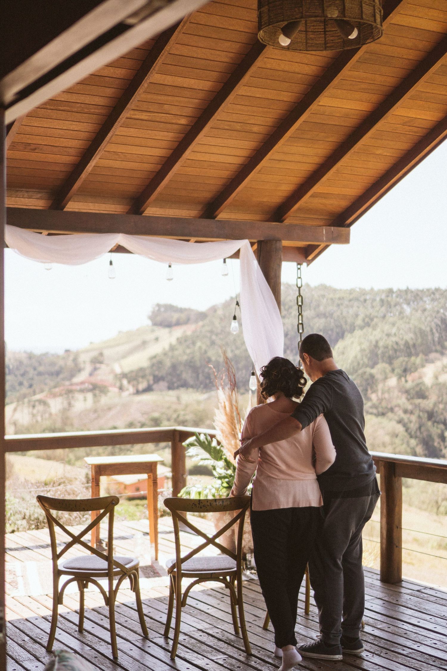 Two people sharing an intimate moment on a wooden deck overlooking mountain scenery.
