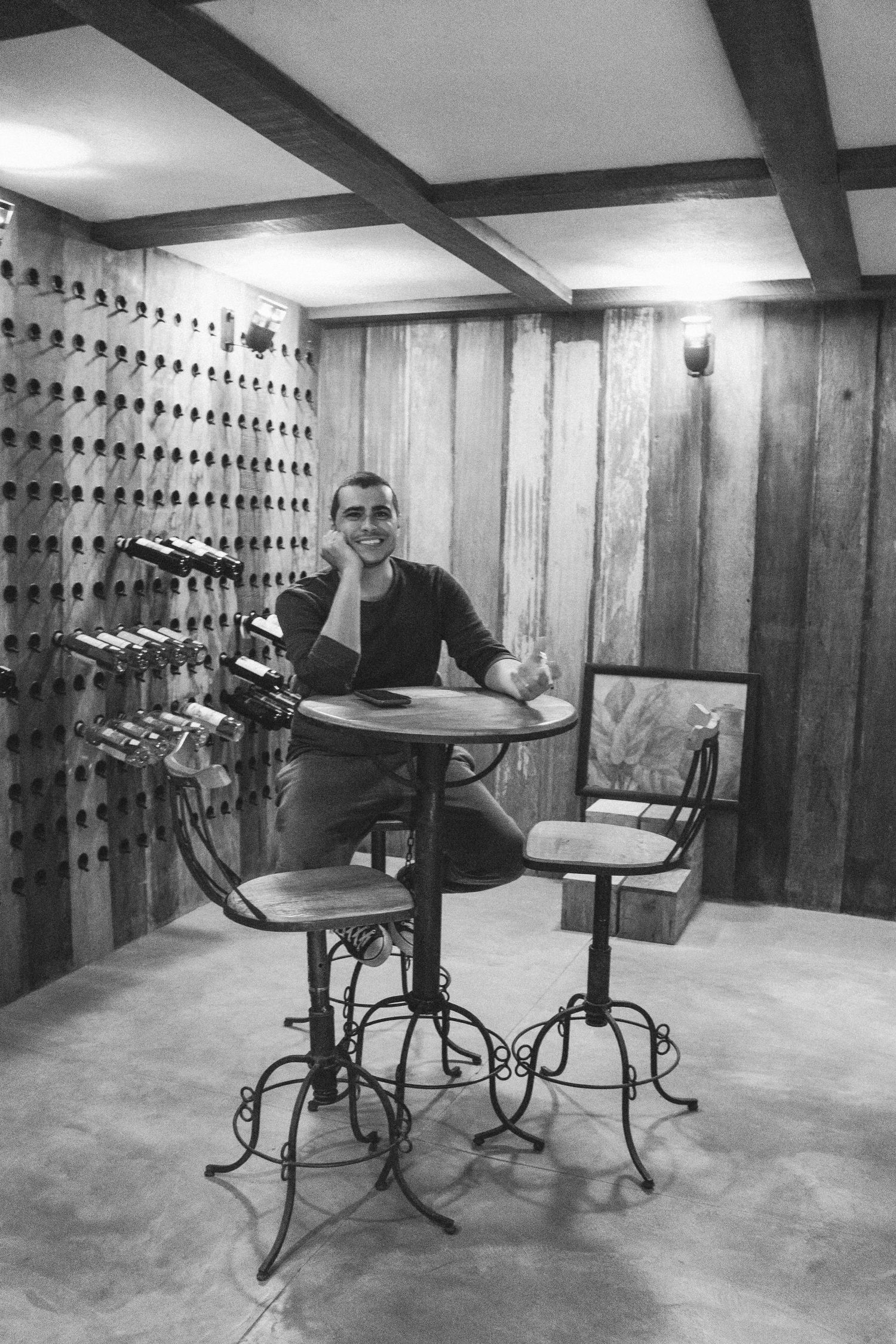 A casual indoor scene with person seated at vintage wrought iron table with wooden walls and mounted decor.