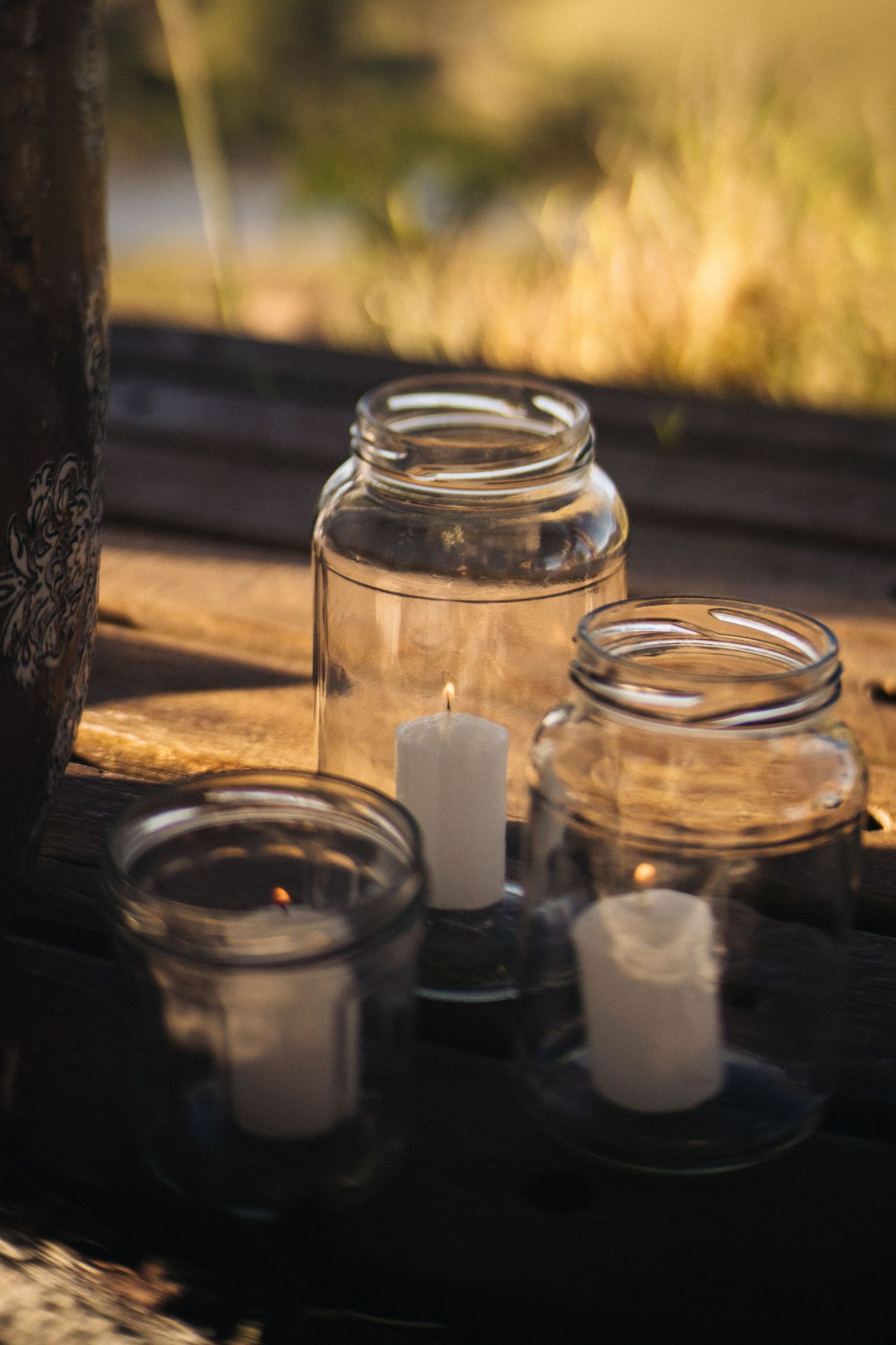 Mason jar candle holders with white candles glowing in golden sunlight.