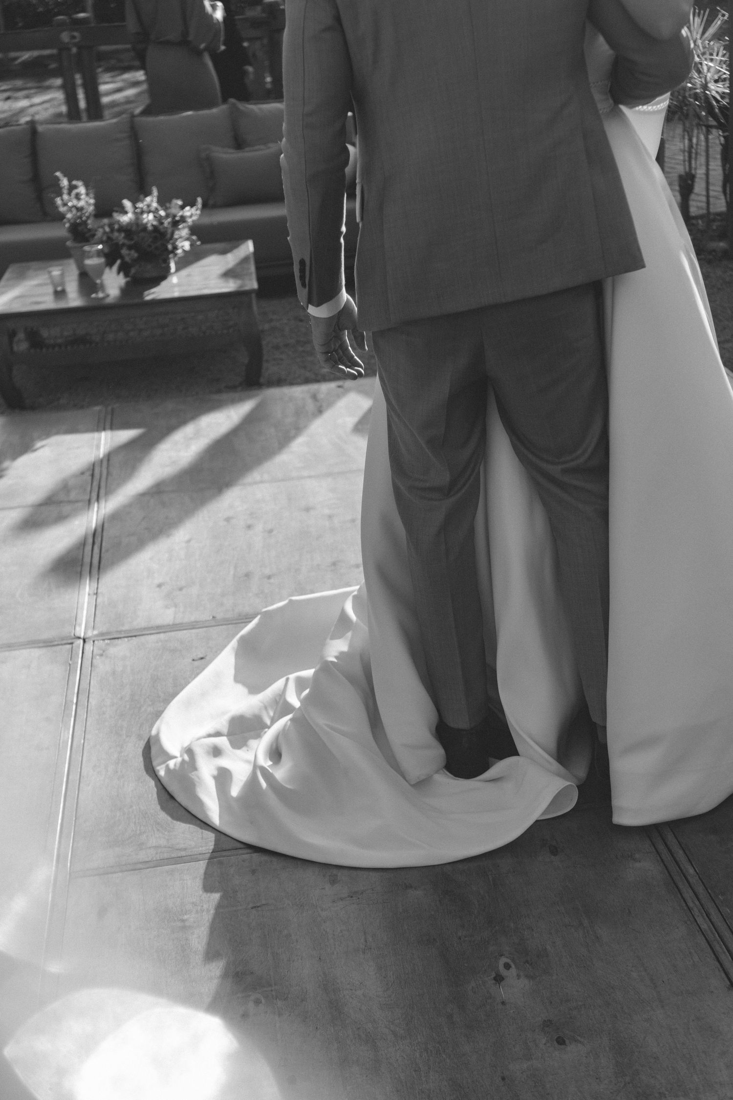 Fotografia de casamento em preto e branco com casal de recém casados dançando juntos e mostrando detalhes do pés do noivo se entrelaçando co