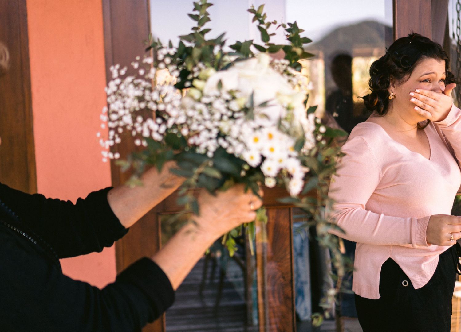 A surprise moment captured as someone presents flowers through an open doorway.