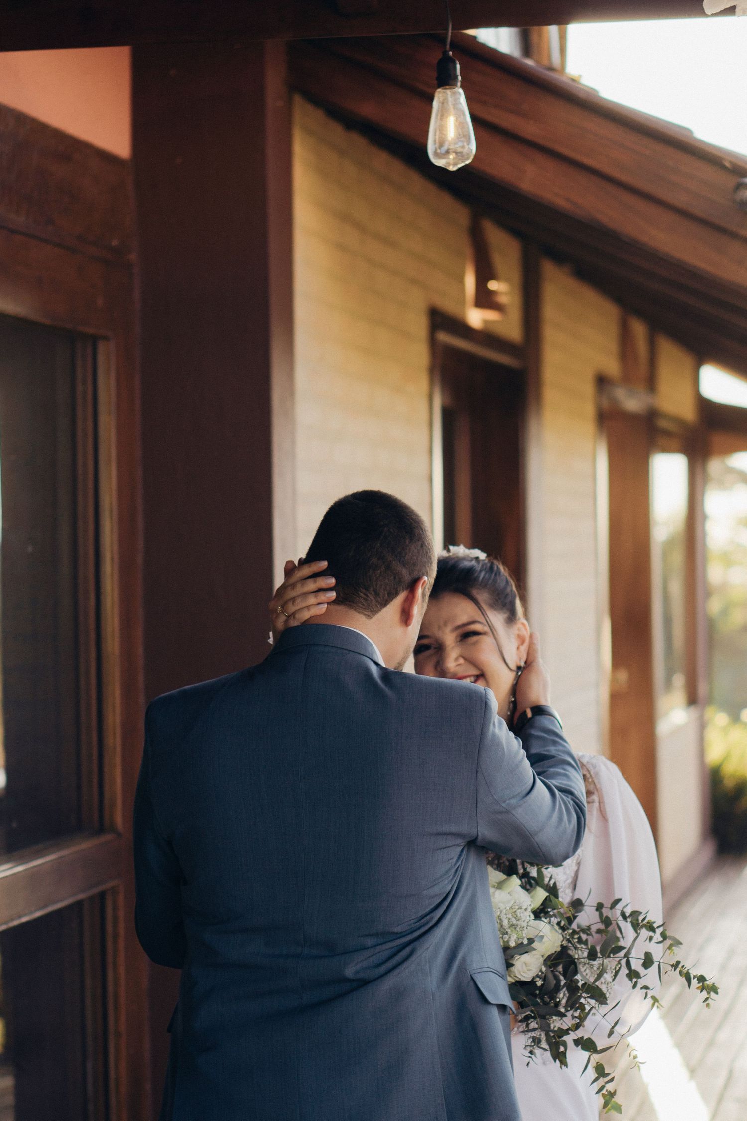 An intimate wedding moment captured on a rustic porch with hanging lights.