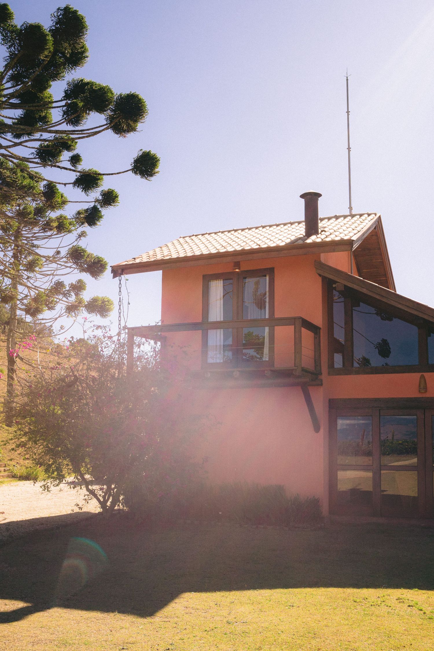 A modern orange mountain cabin with large windows and a sloped roof captured in golden sunlight.