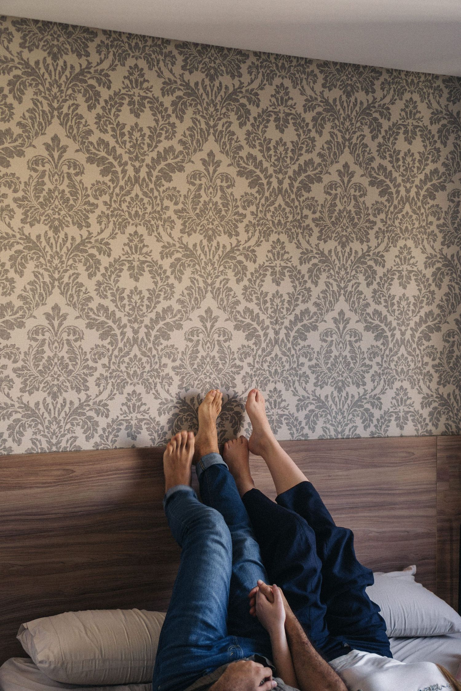 Casal deitado na cama com os pés para cima apoiados na parede © Clara e Matheus Fotógrafos de Casamentos