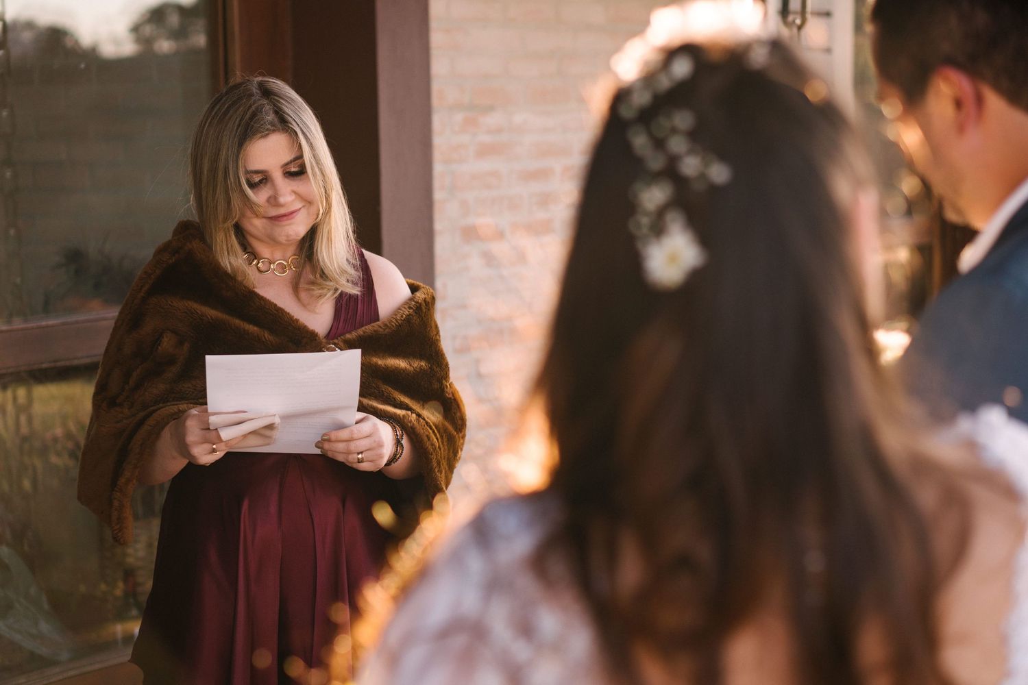 Someone reading from a paper during a wedding ceremony on a rustic porch.