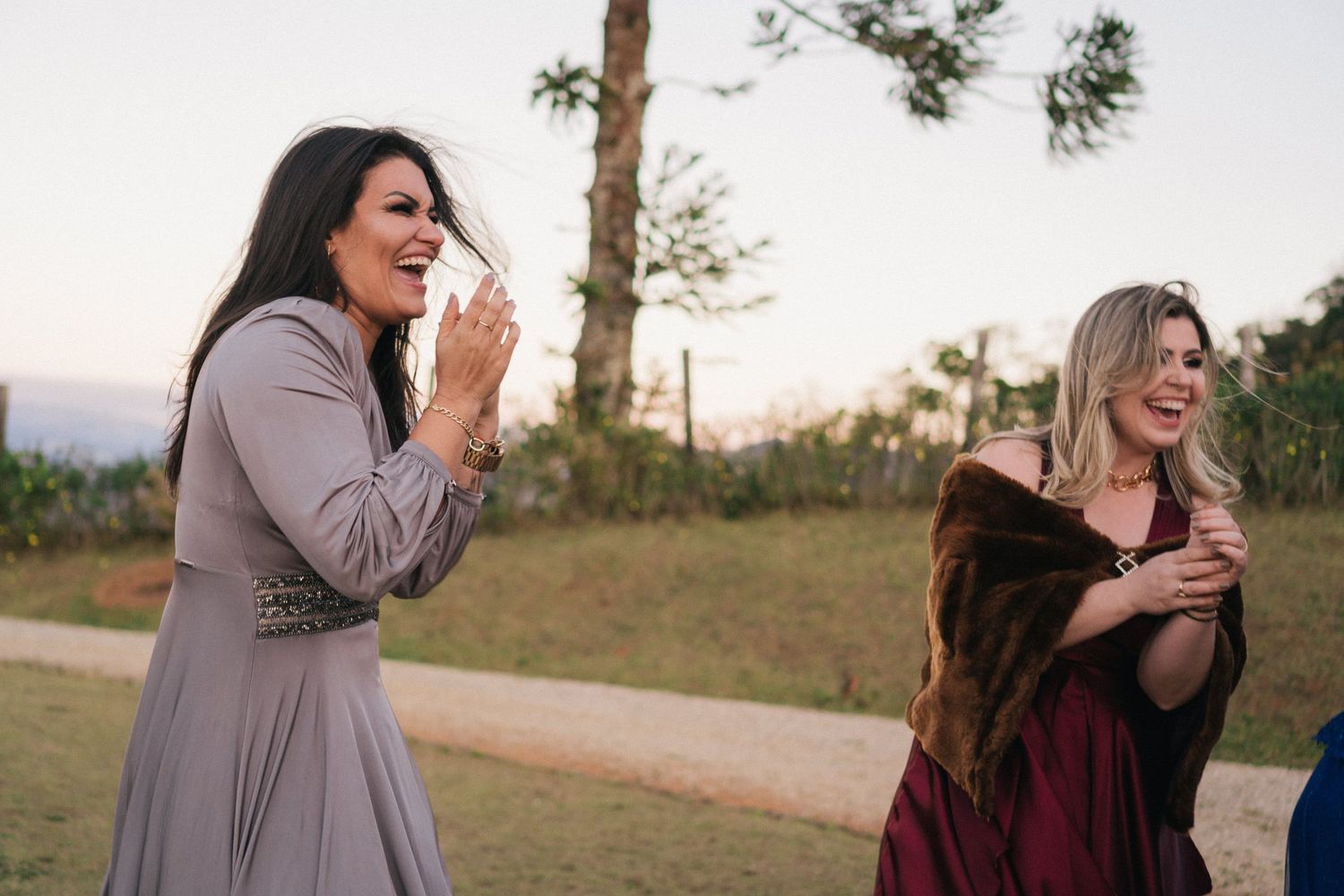 Convidados do casamento compartilham um momento alegre de risadas ao ar livre durante o pôr do sol.