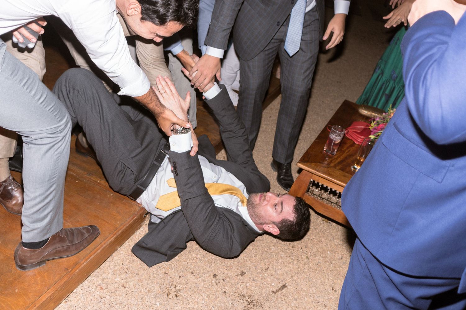 Noivos e padrinhos ajudando um dos amigos a se levantar do chão após ter caído de tanto dançar, fotografia de casamento Clara e Matheus