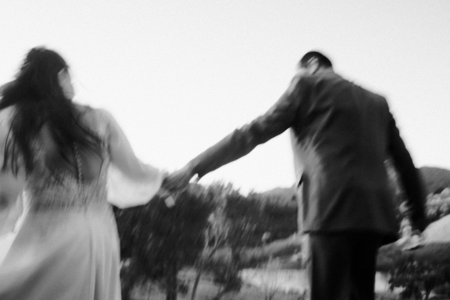 Noivo e noiva correm de mãos dados em fotografia borrada em preto e branco © Clara e Matheus Fotógrafos para Casamentos
