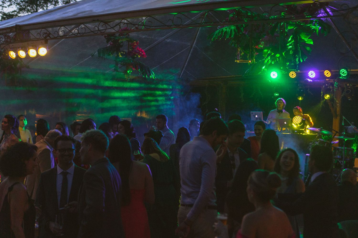 Convidados do casamento dançando na festa com luzes coloridas que iluminam a pista de dança. Todos reunidos e celebrando a festa com os noiv
