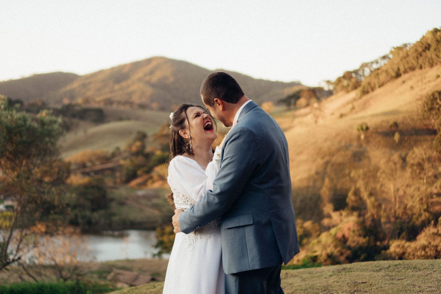 A romantic moment between newlyweds embracing against a scenic mountain landscape.