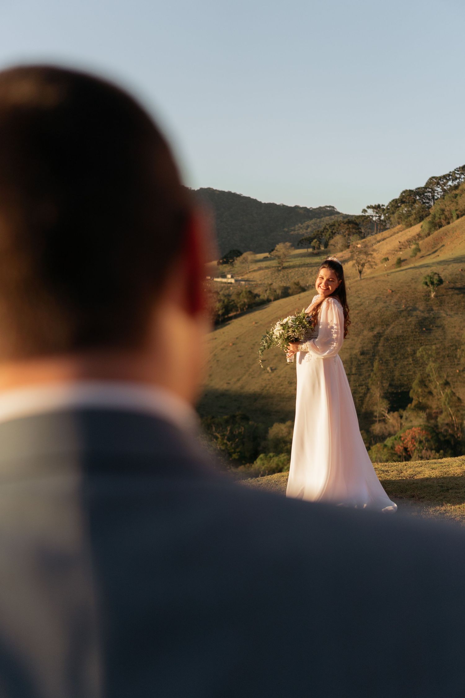 Um momento romântico de casamento capturado em meio às colinas durante a hora dourada.