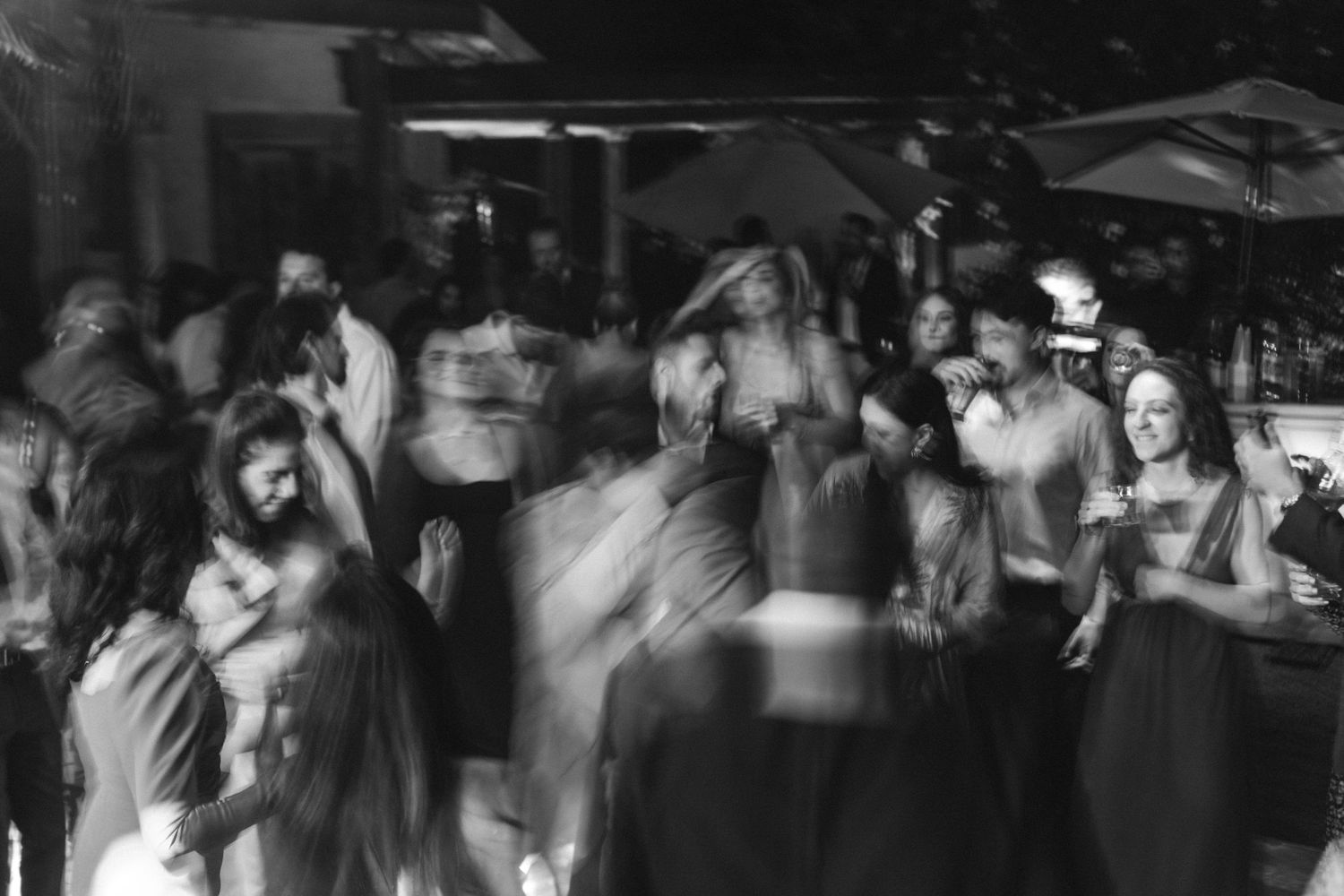 Fotografia em preto e branco em movimento mostrando as pessoas dançando durante festa de casamento