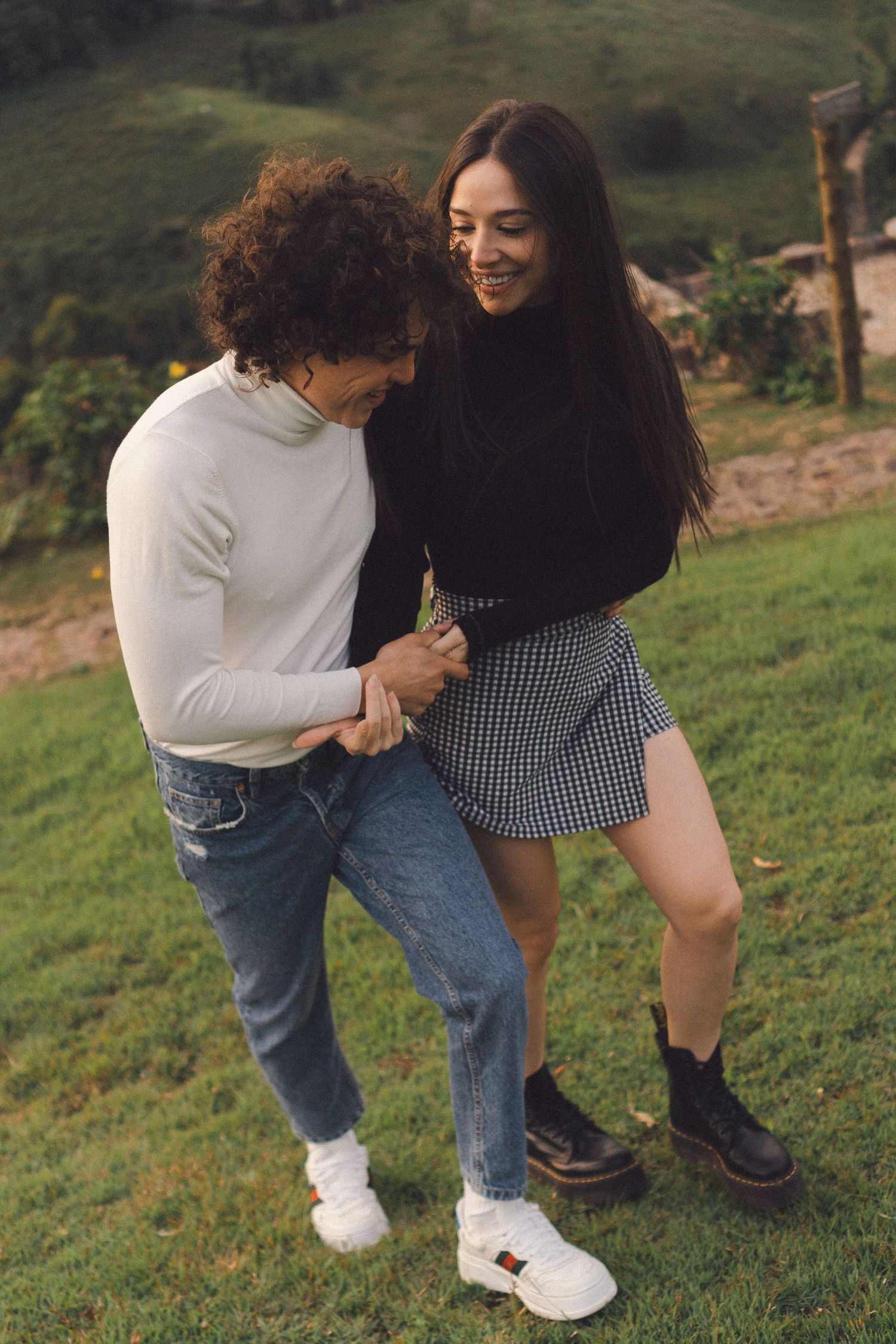 Uma sequência de fotos mostrando duas pessoas se abraçando e se acariciando em uma encosta gramada, vestindo roupas casuais.