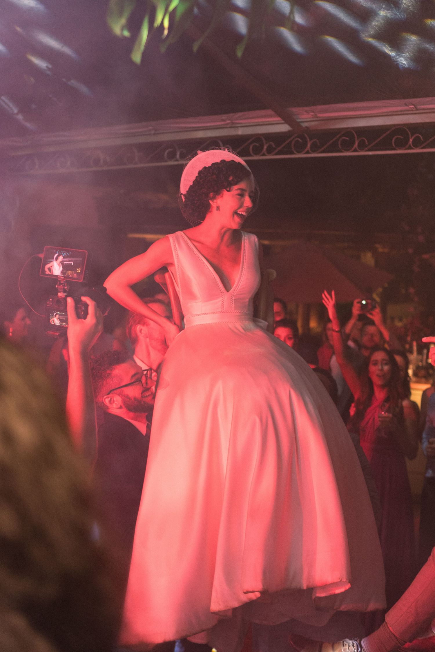 Noiva sendo levantada por amigos e sendo coberta por um luz vermelha durante a festa de casamento