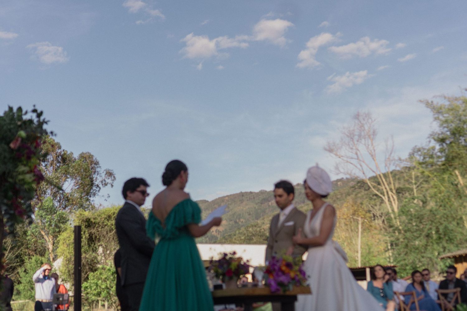 Casamento ao ar livre em um cenário com montanhas de fundo em um dia ensolarado.