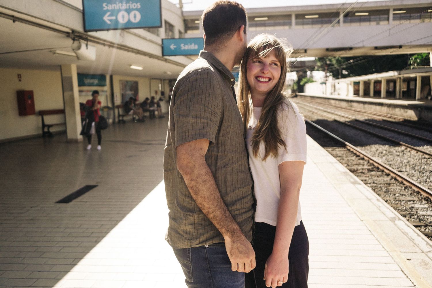 Um casal compartilhando um momento de alegria enquanto estão na plataforma de uma estação de trem.