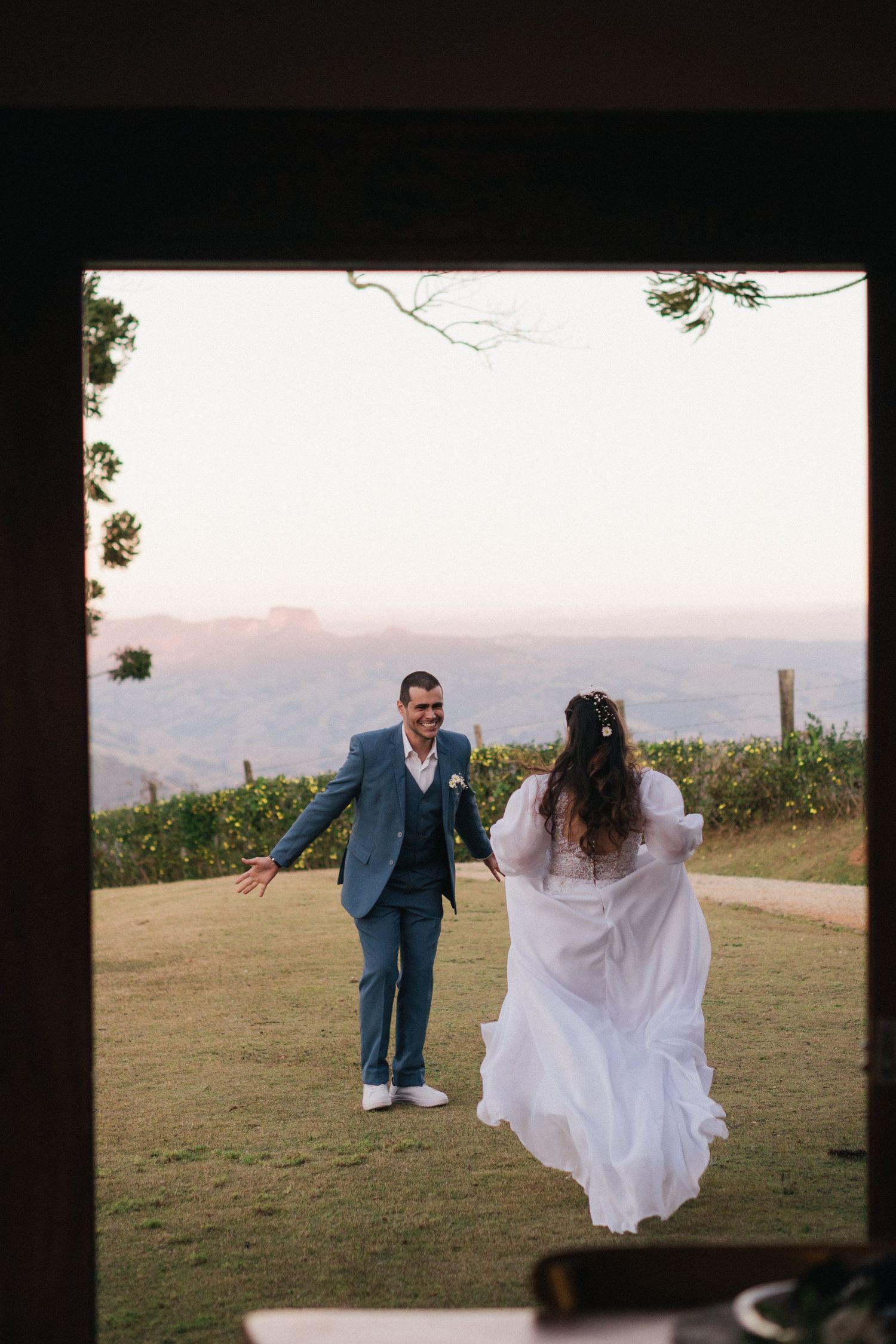 Um casal dança junto em um mirante panorâmico com montanhas e pôr do sol ao fundo.