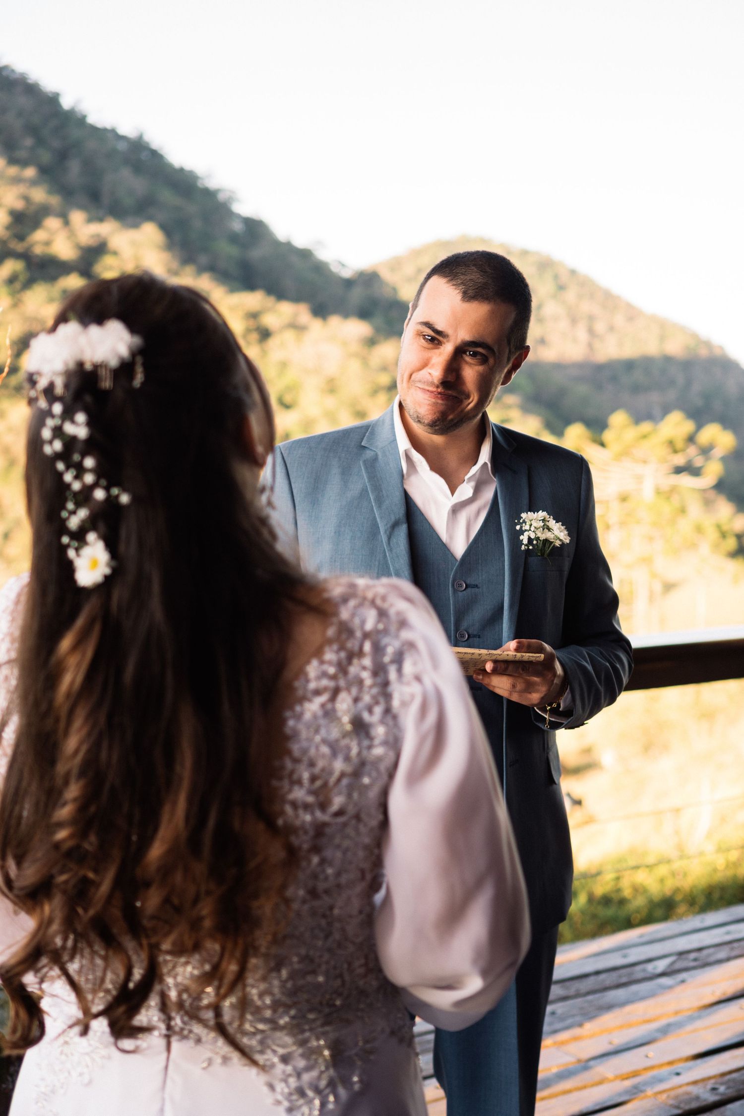 Bride and groom sharing emotional moment during outdoor wedding ceremony with mountain backdrop.