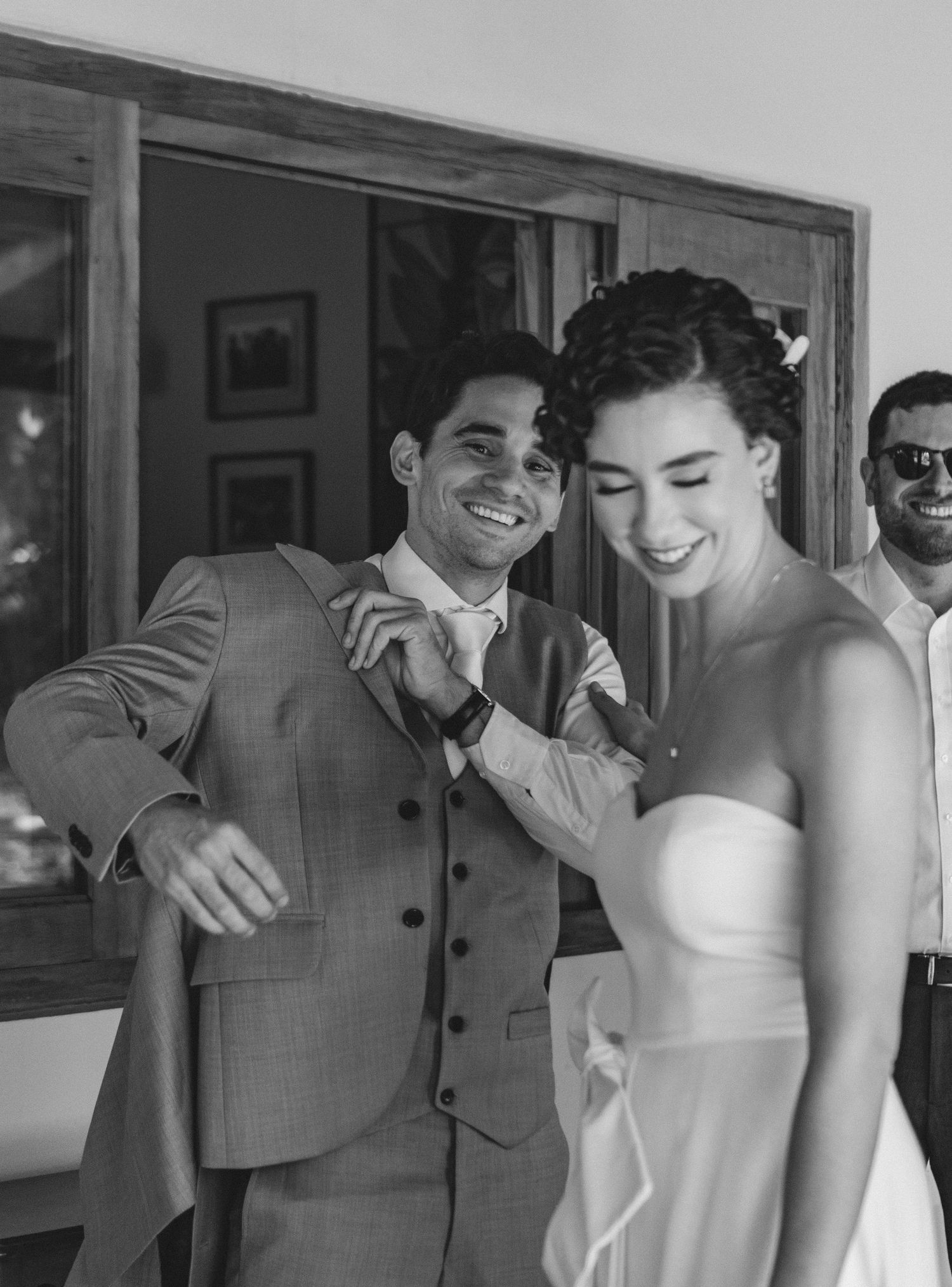 Casal feliz compartilhando um momento espontâneo em seu dia de casamento, com a noiva em vestido branco tomara que caia