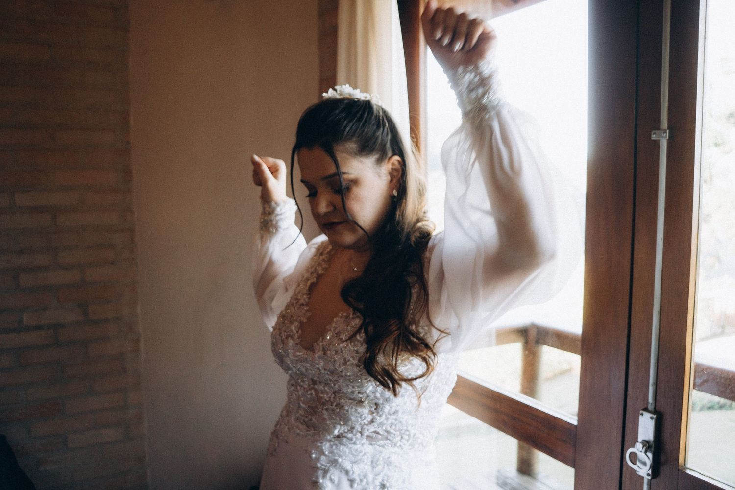 Person in white lace dress dancing joyfully near a window.