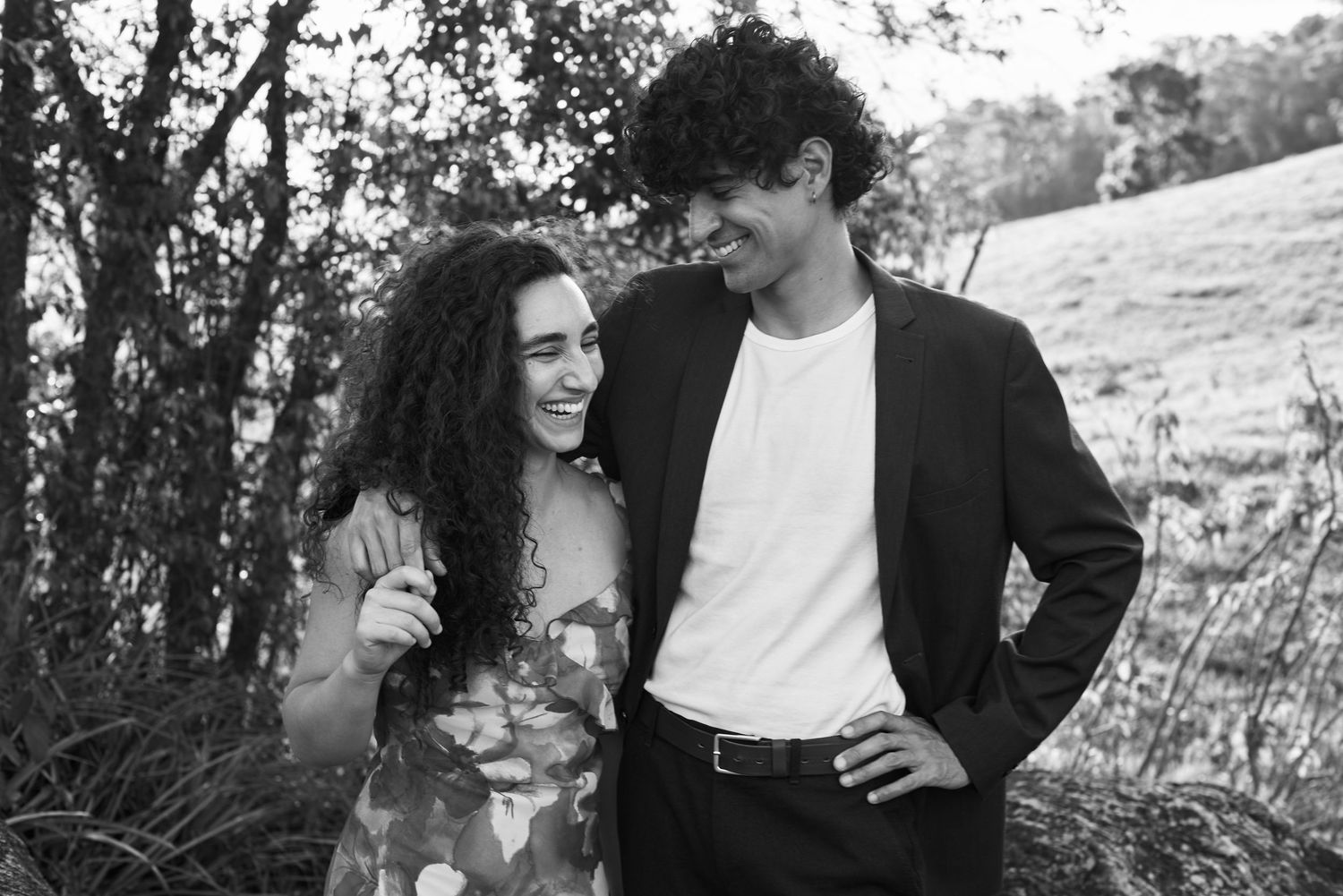 Fotos românticas em preto e branco de um casal, retratando momentos íntimos e risos em um ambiente natural ao ar livre.