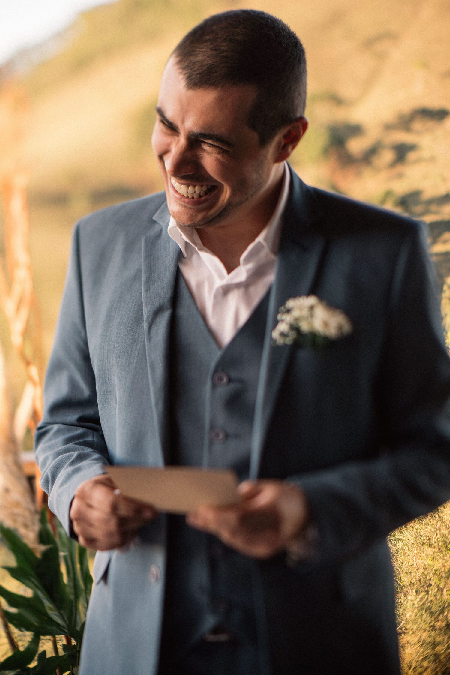 A joyful candid moment during a wedding ceremony with golden hills in the background.