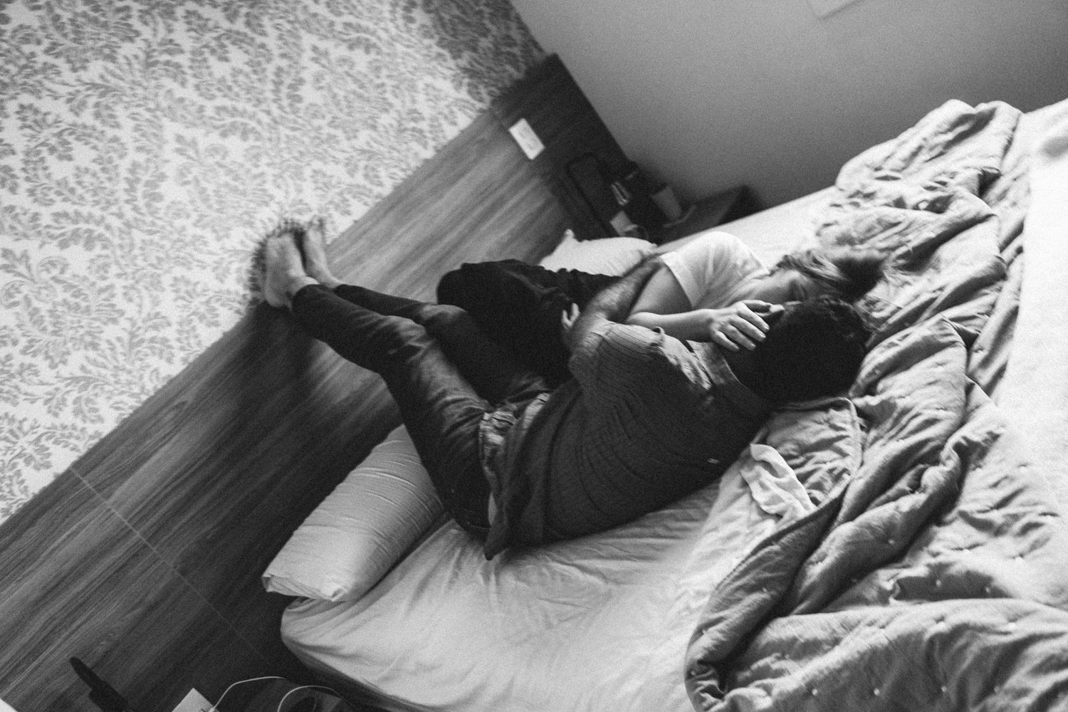 Couple kissing passionately in the bed upside down for a photoshoot. Black and white picture. Picture by Matteo and Clar