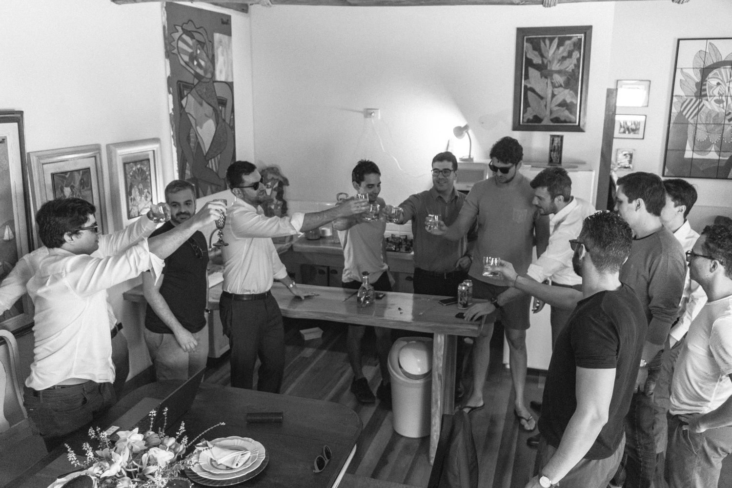 Grupo de amigos do noivo fazendo um brinde durante a preparação do noivo, celebrando o dia do casamento com alegria