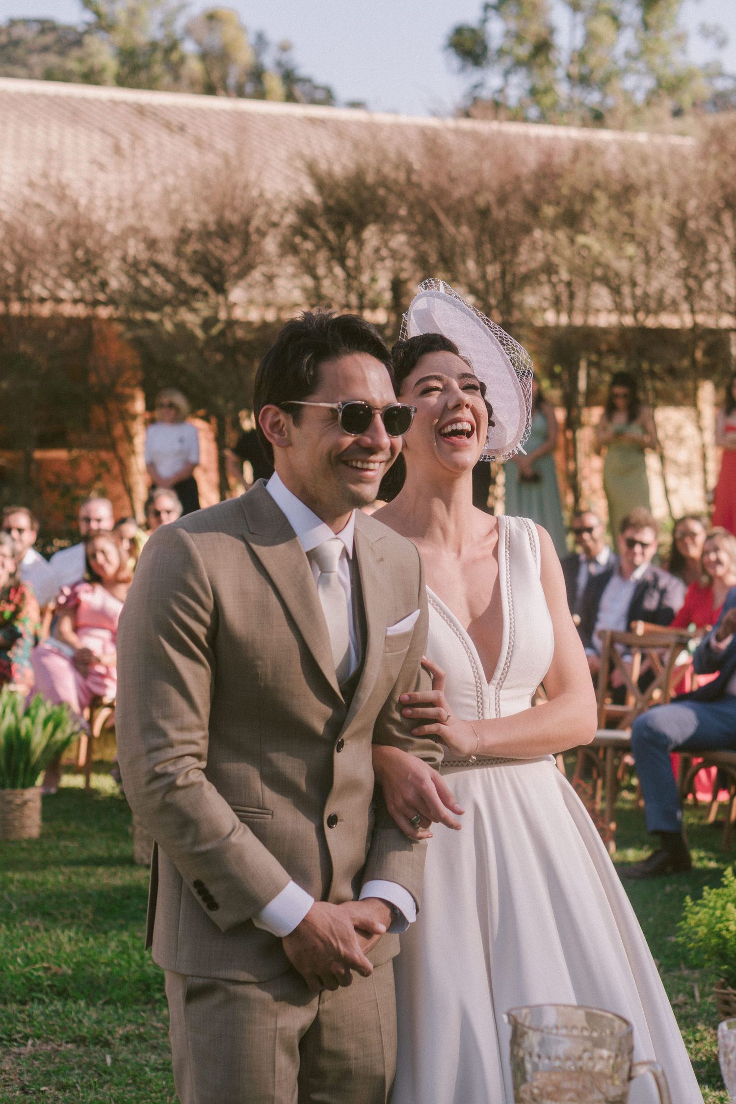 Um casal feliz compartilha um momento espontâneo de risada durante a cerimônia de casamento ao ar livre em um dia ensolarado
