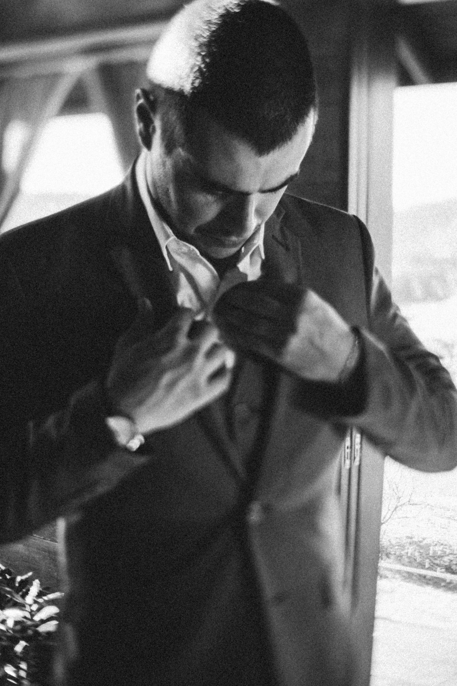 Black and white portrait of someone adjusting their formal suit tie.