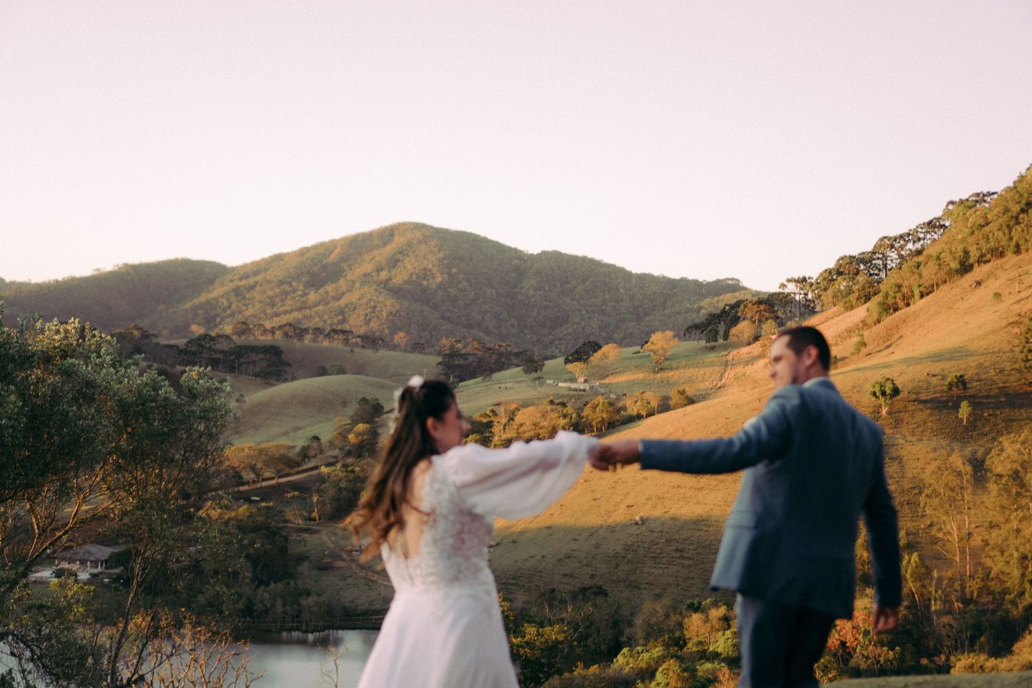 Casal dança junto no topo de uma colina durante a celebração do casamento ao pôr do sol.