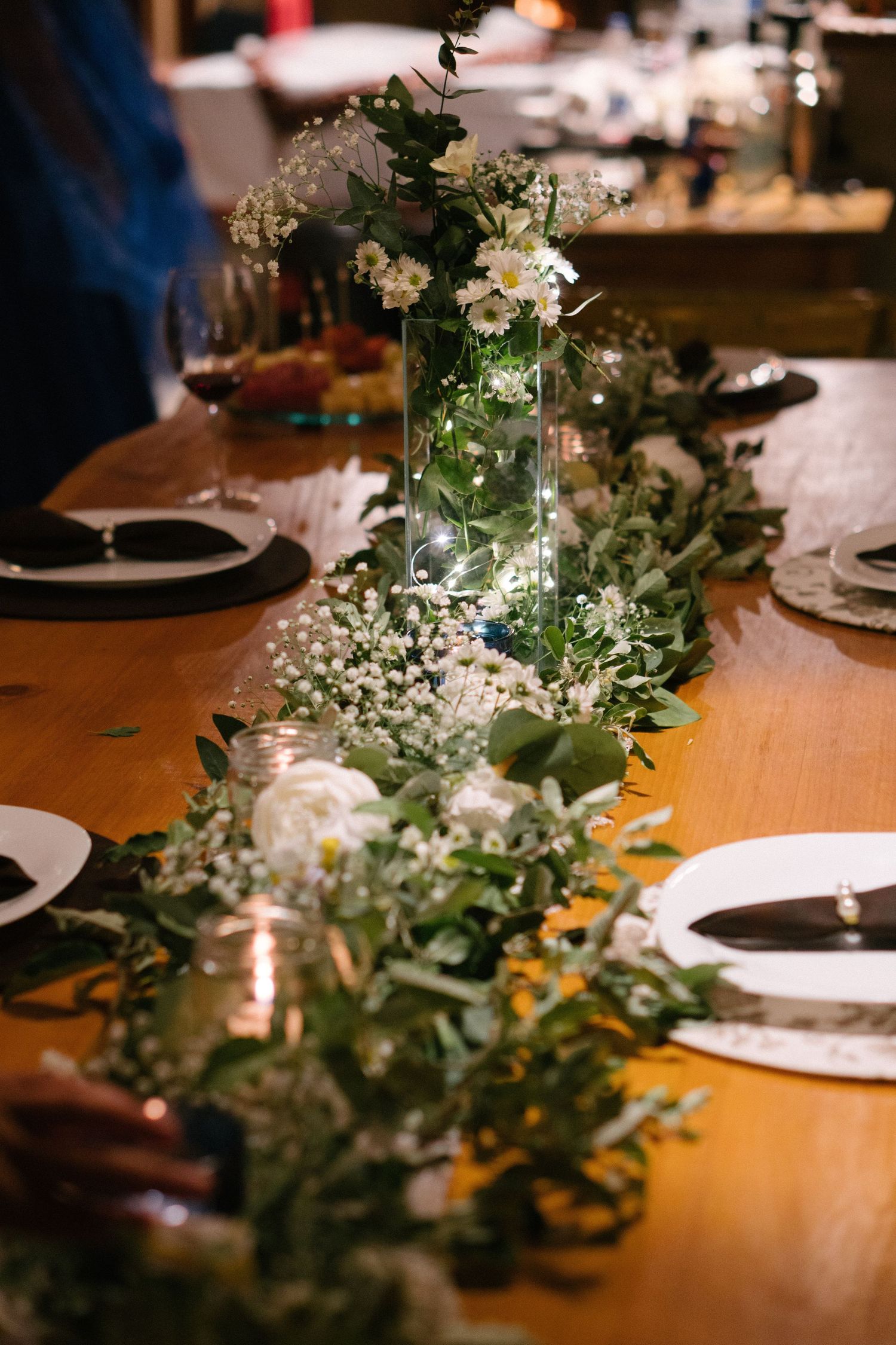 Elegante arranjo de mesa de casamento com centro de mesa com flores brancas e caminho de mesa com guirlanda de folhagens.