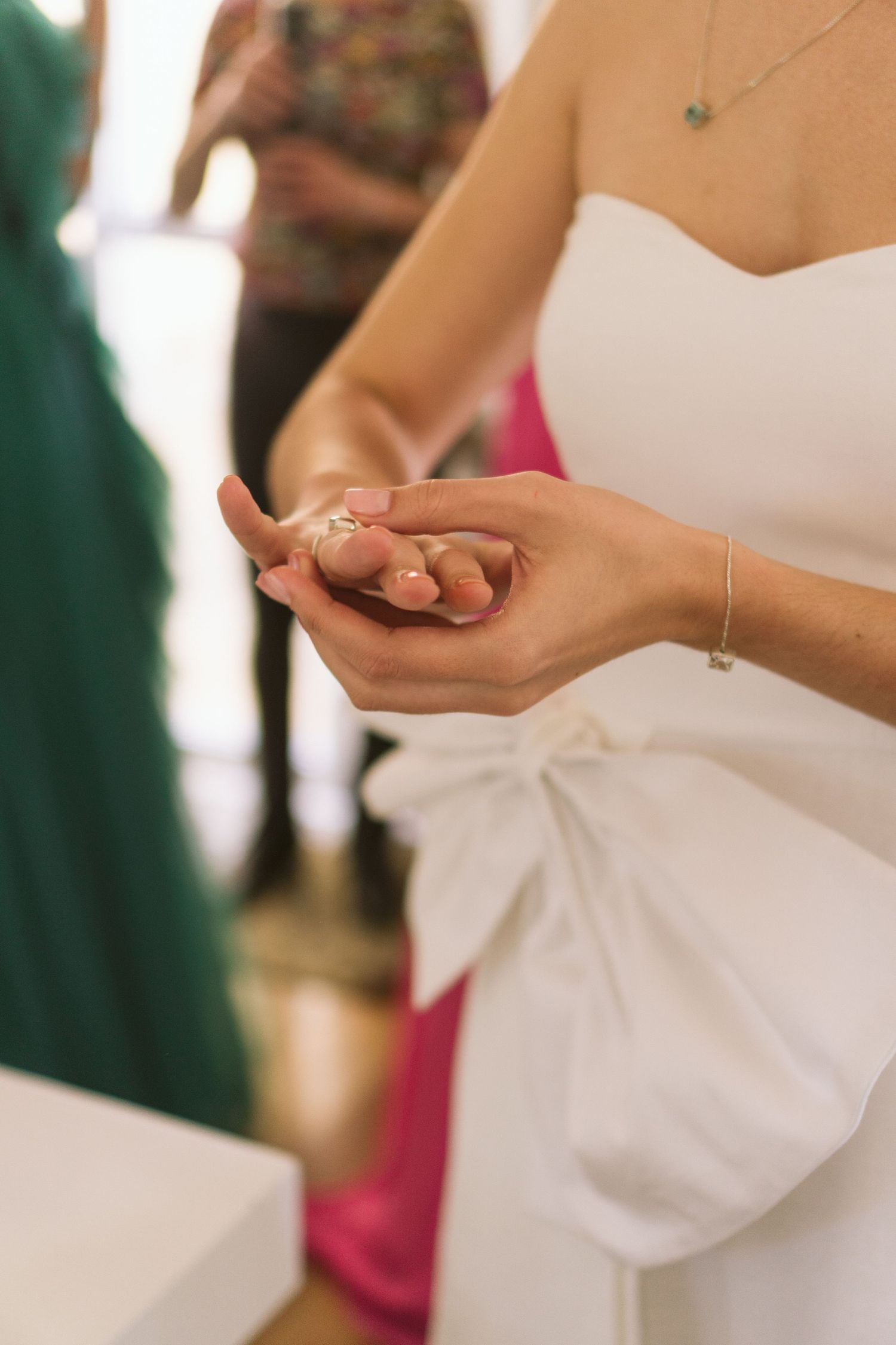 Vista de perto das mãos da noiva segurando o delicado anel de noivado antes da cerimônia de casamento, com vestido branco