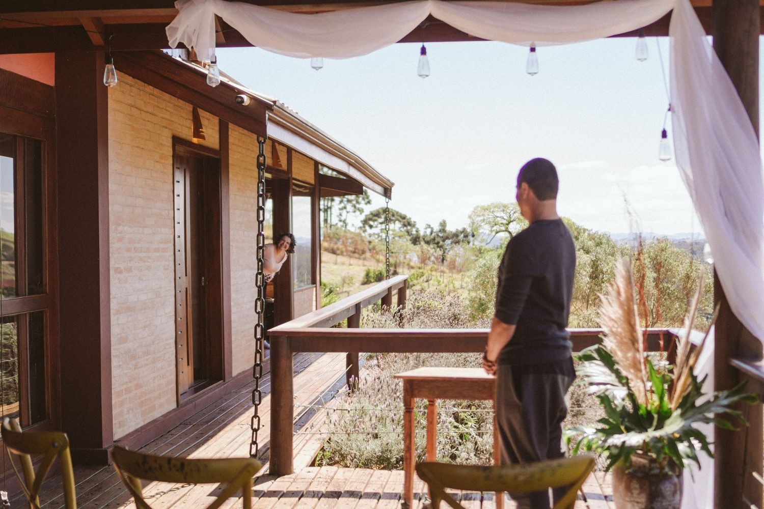 A person stands on a decorated porch overlooking a scenic landscape.