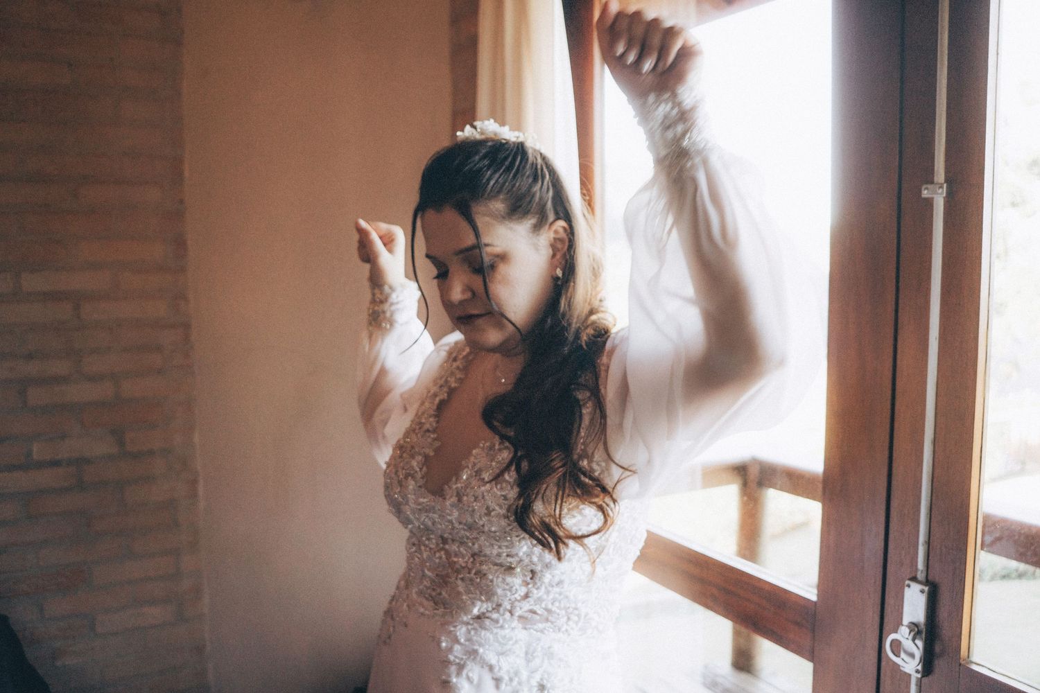 Joyful dancing captured in a sunlit room wearing an elegant lace wedding gown.