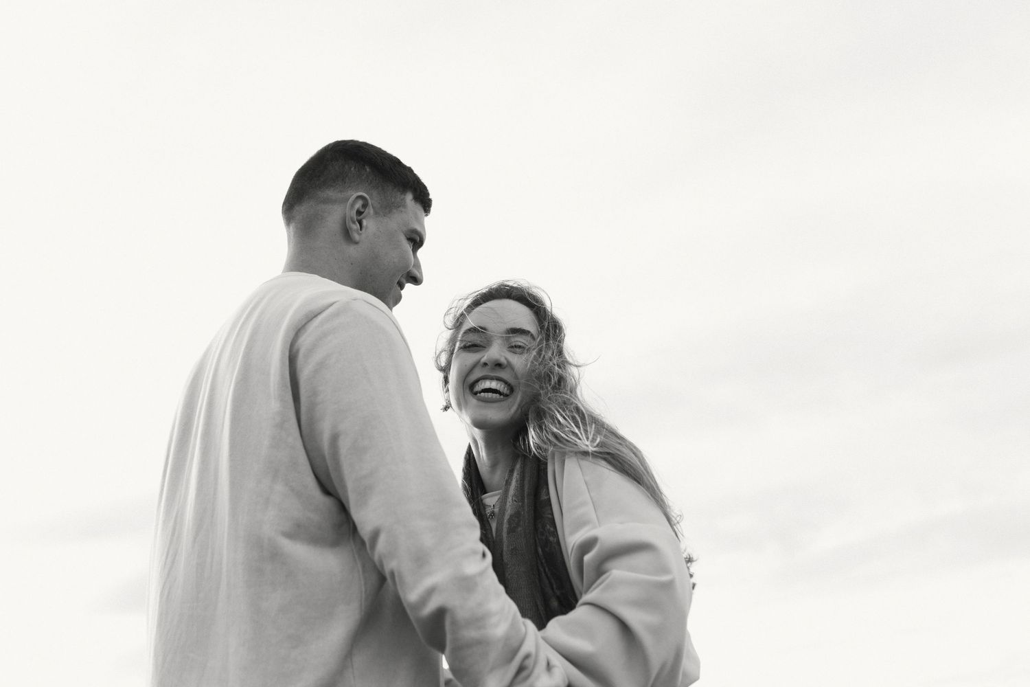 Uma série de fotos em preto e branco que mostram momentos românticos de um casal se abraçando e se beijando ao ar livre.