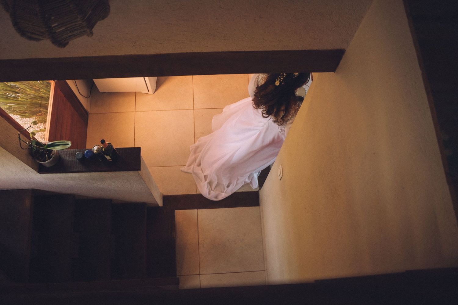 An overhead view of a person in a white dress walking on a tiled floor.