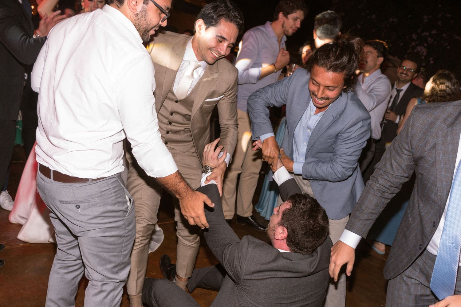 Noivos e padrinhos levantando um dos amigos do chão após ter caído de tanto dançar, fotografia de casamento Clara e Matheus