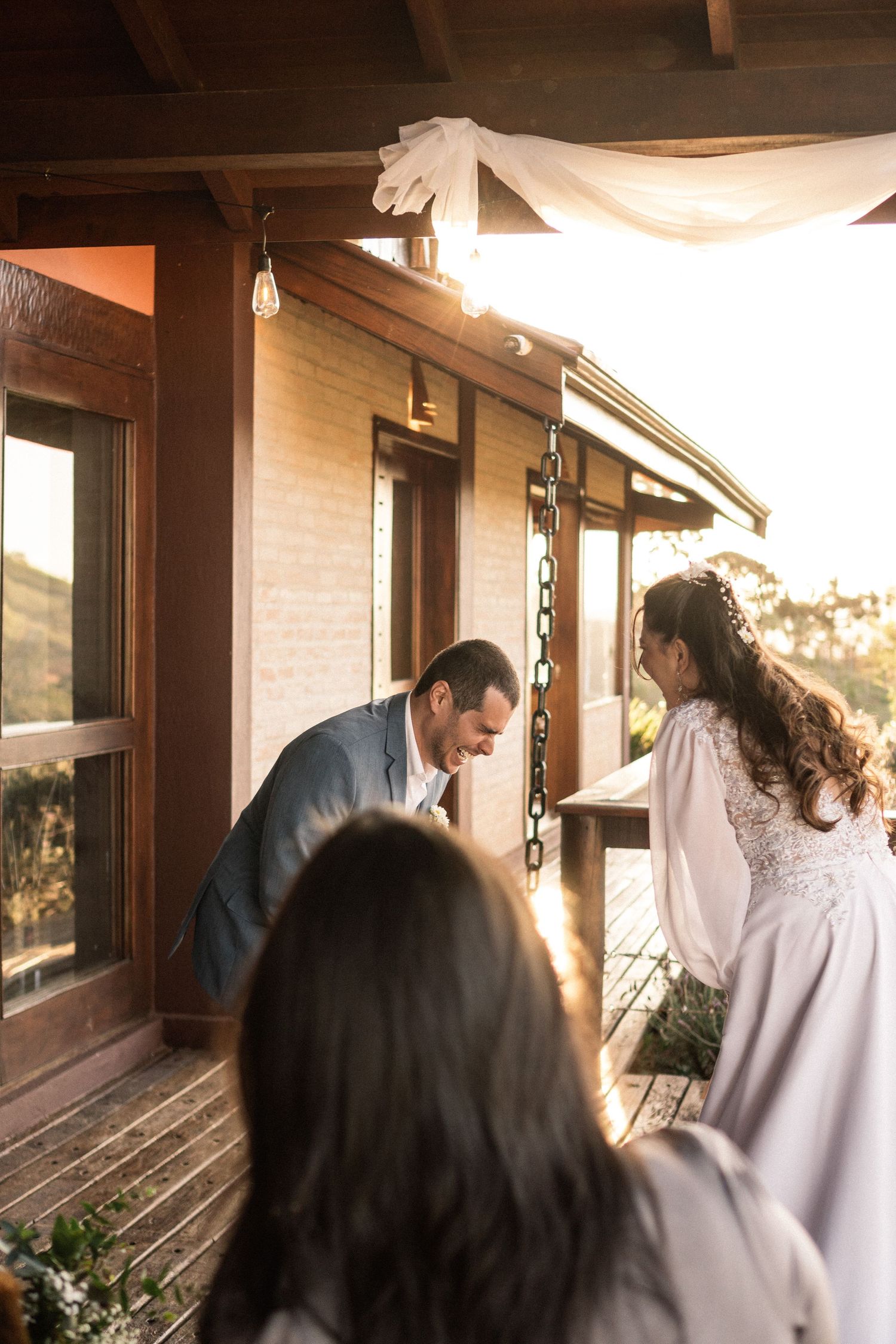 Couple exchanging vows during an intimate outdoor wedding ceremony on a rustic wooden porch at sunset.
