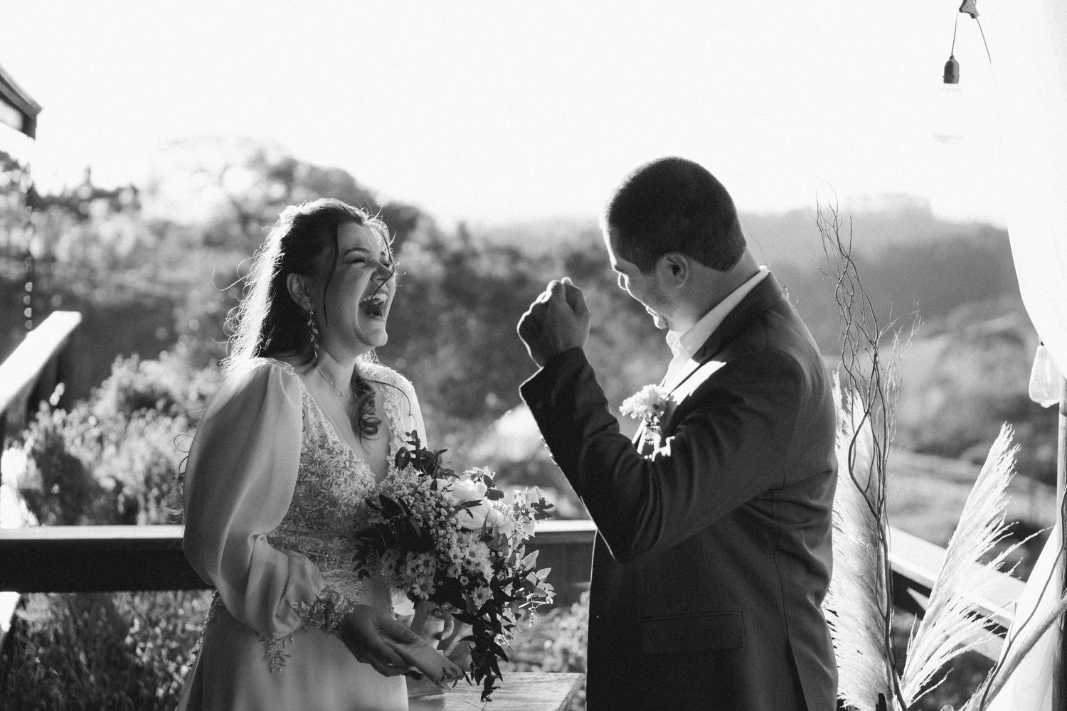 A black and white wedding photo showing an emotional moment on an outdoor deck.