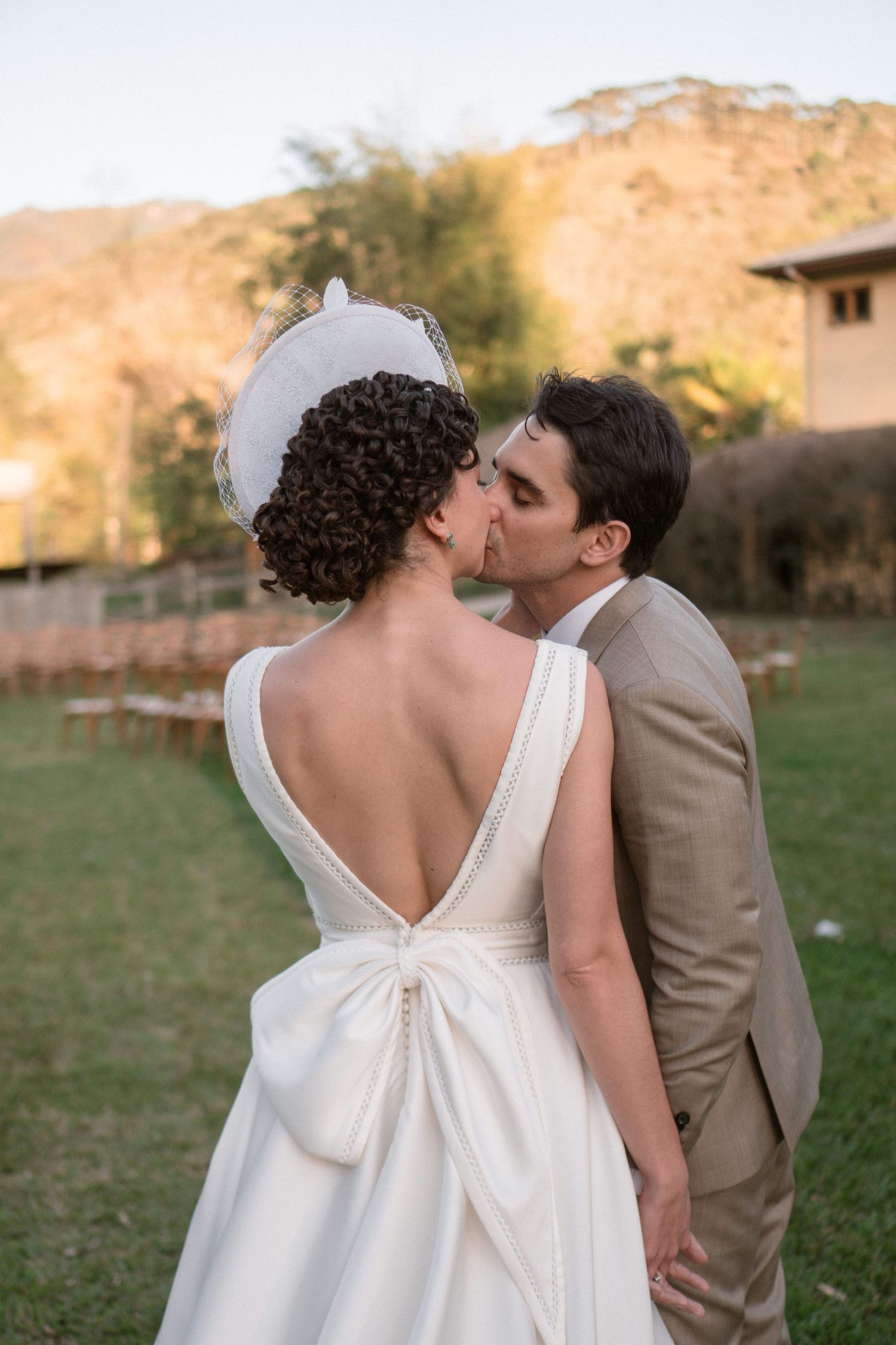 Casal apaixonado em um casamento ao ar livre, com vista para as montanhas. A noiva usa um elegante vestido branco de costas em V e o noivo u