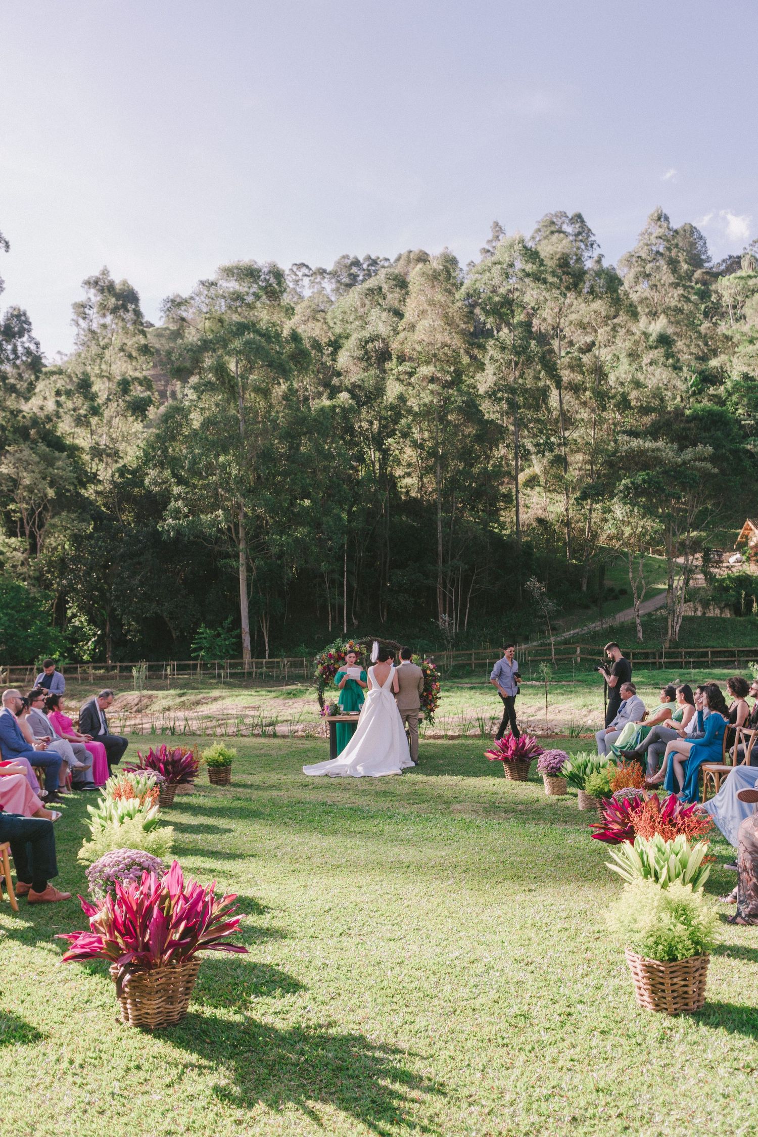 Fotografia de casamento ao ar livre: Cerimônia romântica com eucaliptos e arranjos florais rosa, ideal para inspiração de decoração de casam