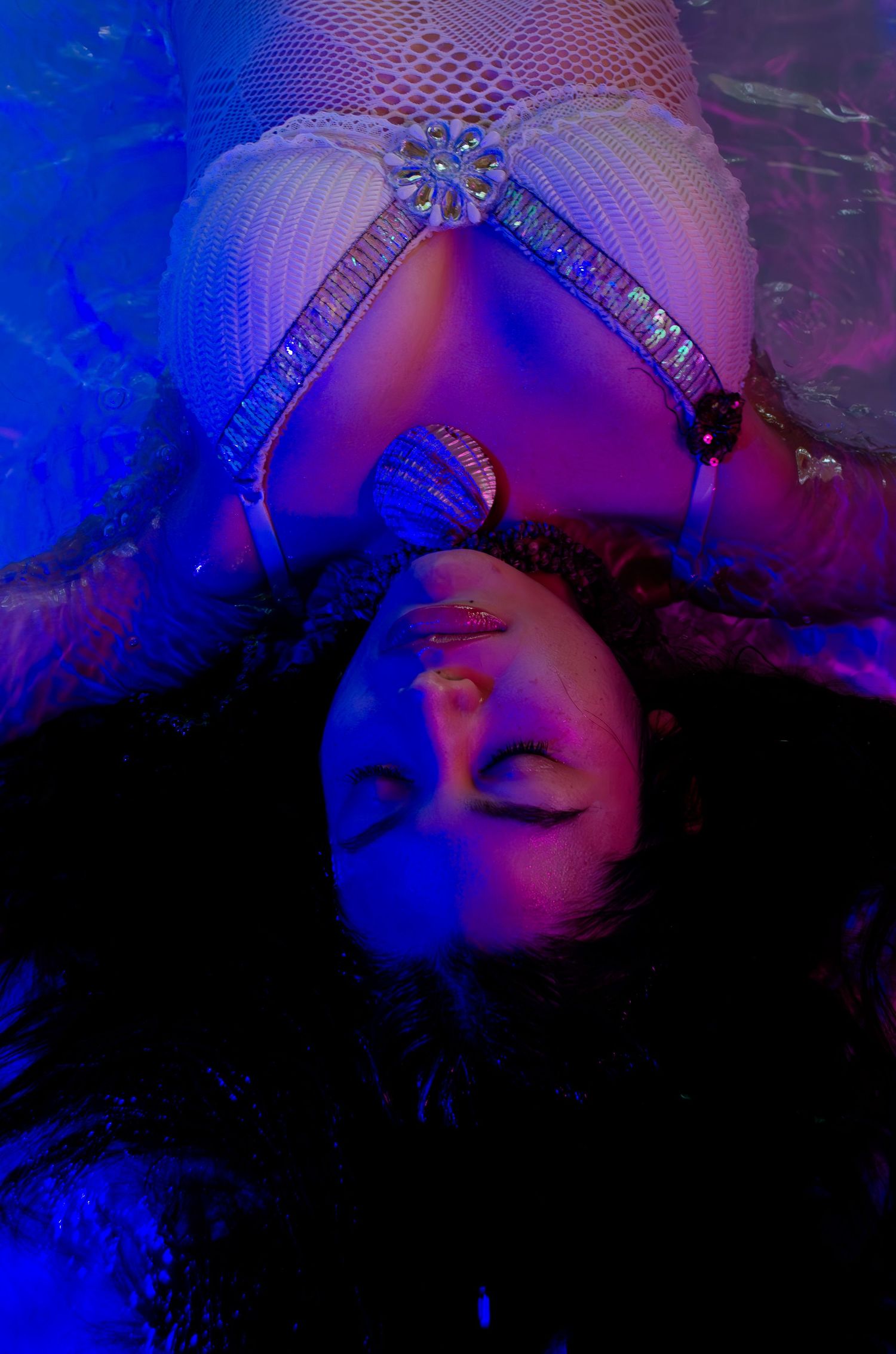 Experimental photoshoot in water. Red & blue LED lights with a use of a pool at an indoor studio.