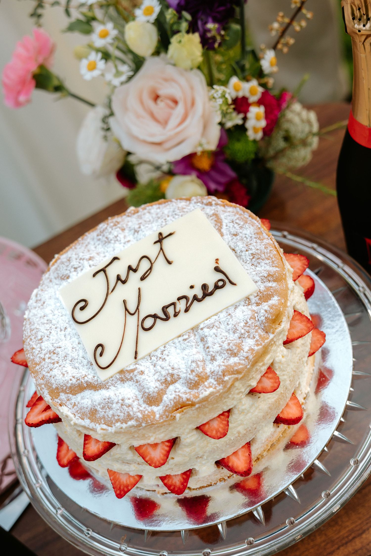Three layered cream cakes decorated with strawberries and powdered sugar on glass plates.