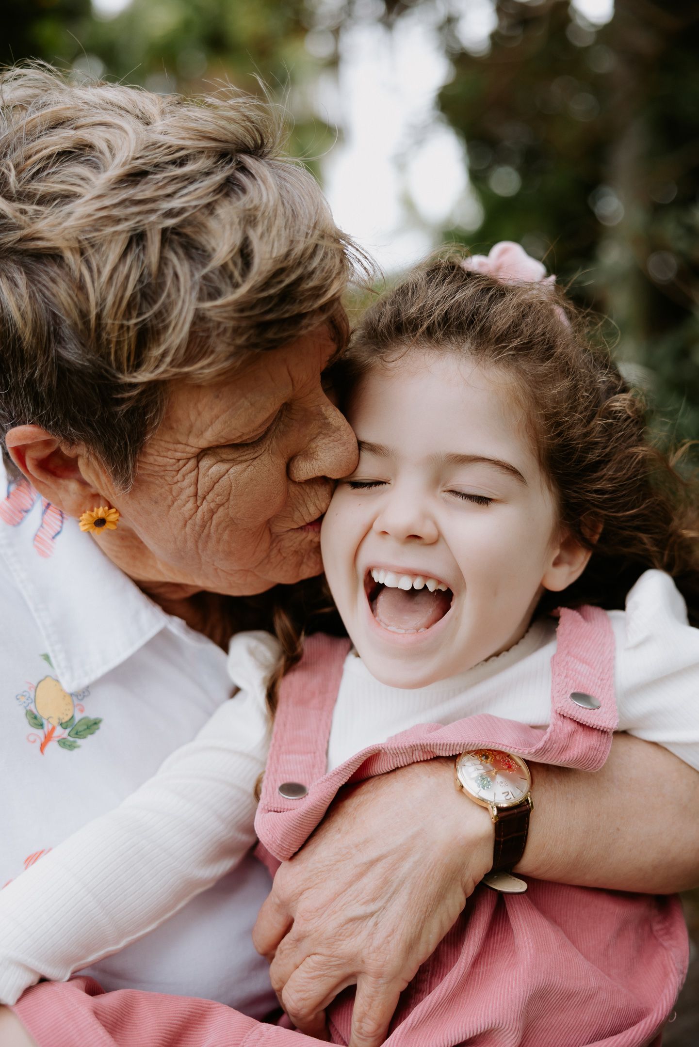 A joyful moment of laughter and affection shared between two people in a garden setting.