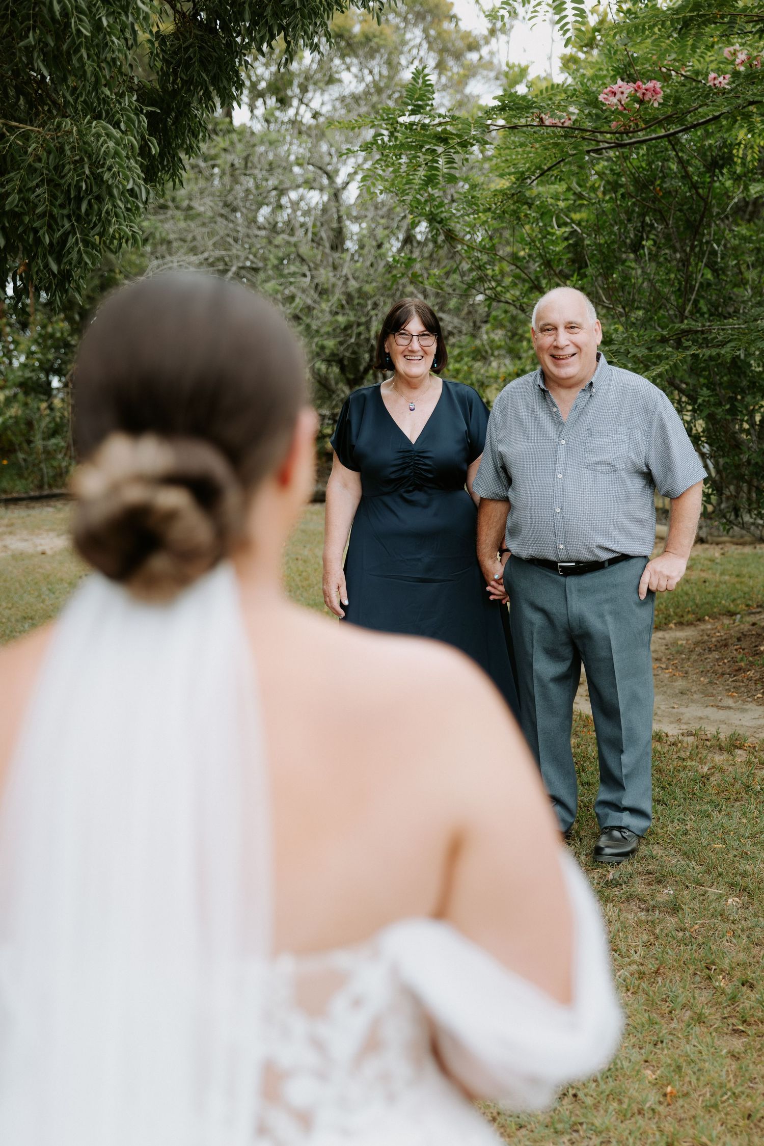 Outdoor wedding moment with couple standing among trees and greenery.