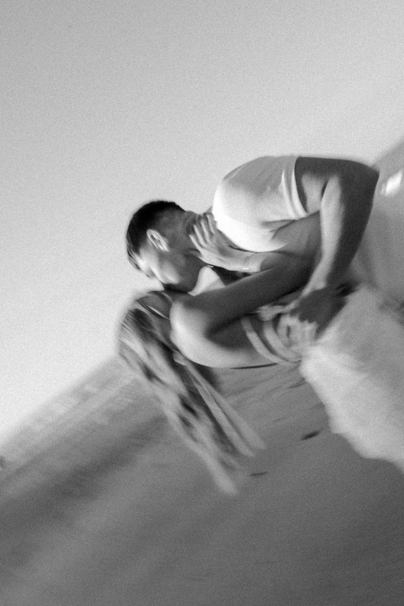 Blurred black and white photo of two people embracing in motion, creating an artistic, dreamy effect.