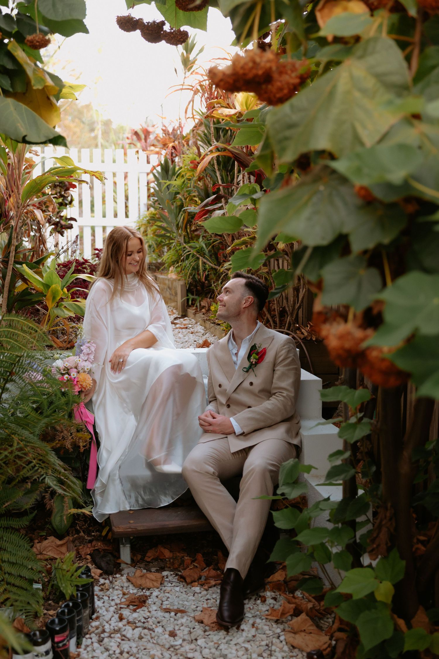 Couple sharing a romantic moment on a stone path surrounded by garden foliage.