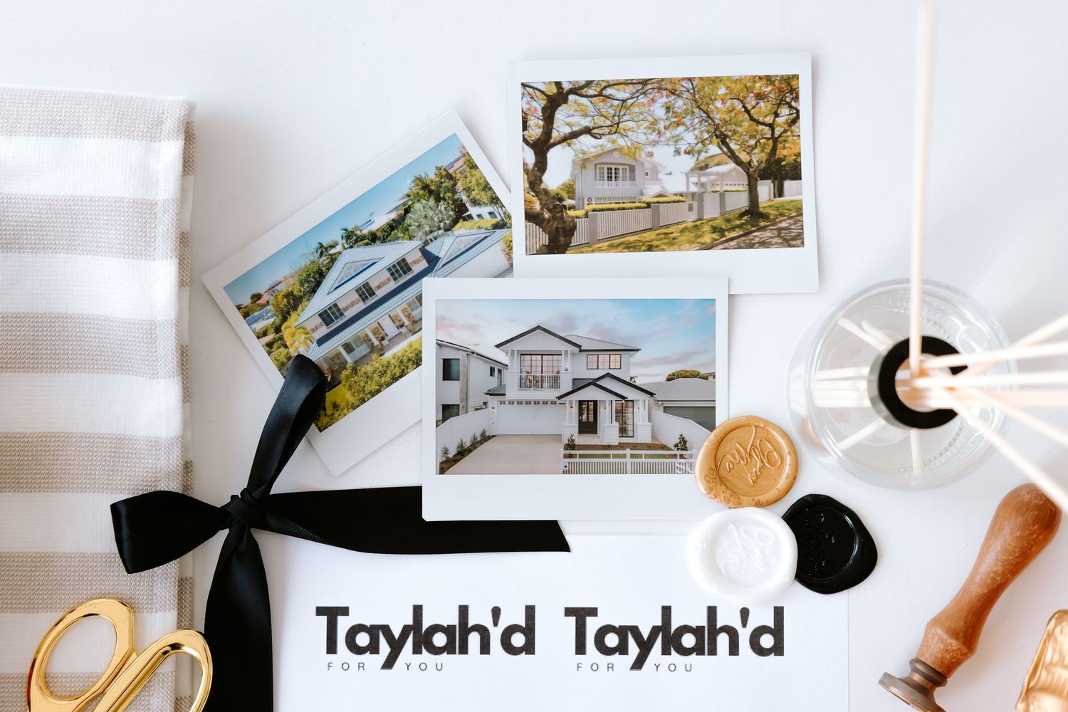Taylahd real estate branding flatlay with property photos, gold scissors, wax seal, and striped fabric on white background.